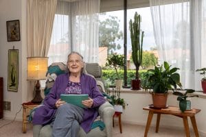 Elderly woman sitting holding tablet device