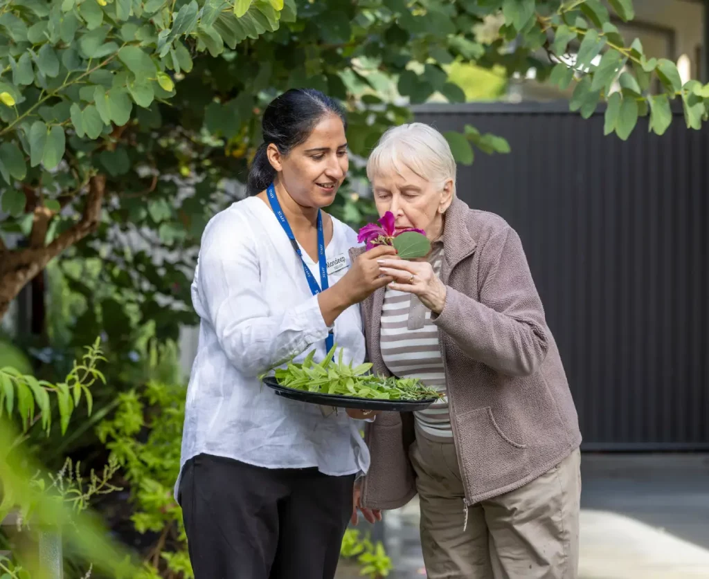 Elderly woman smelling rose