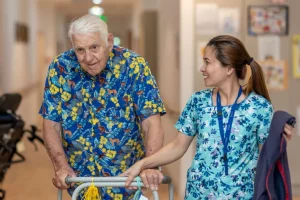 man with zimmer-frame supported by carer