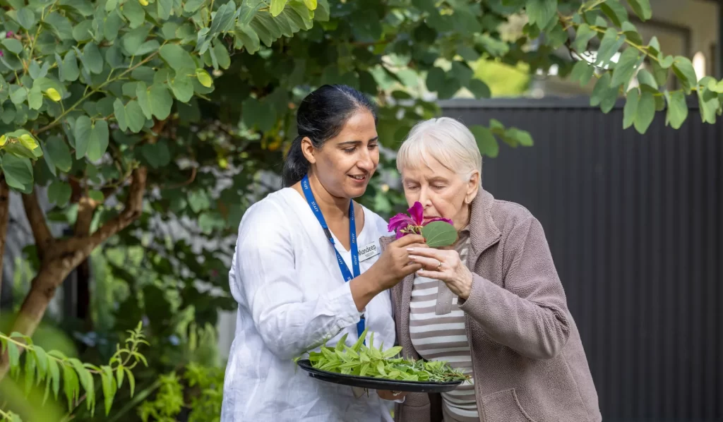 Elderly woman smelling rose